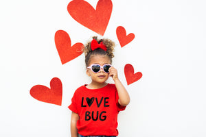 Love Bug Red Toddler Shirt for Valentine's Day worn by little girl wearing pink heart shaped sunglasses and red felt hearts